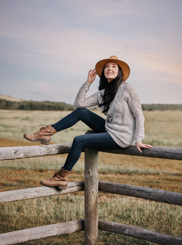 Girl in a hat sits on a farm fence. Countryside. Prairies Stock Photo